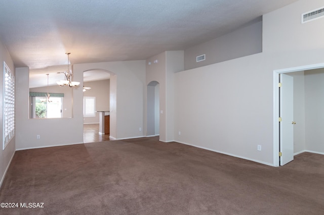 carpeted empty room with a chandelier, lofted ceiling, visible vents, and arched walkways