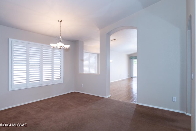 unfurnished room featuring carpet floors, arched walkways, visible vents, an inviting chandelier, and baseboards