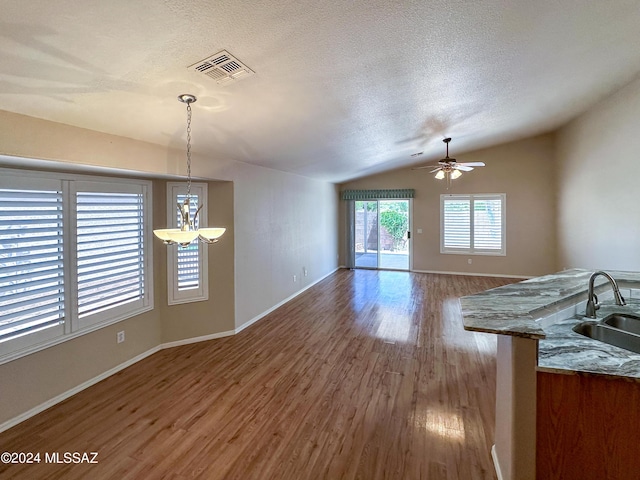 unfurnished living room featuring lofted ceiling, sink, hardwood / wood-style flooring, ceiling fan, and a textured ceiling