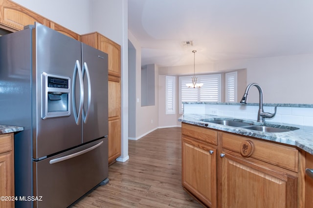 kitchen with an inviting chandelier, sink, light hardwood / wood-style flooring, light stone countertops, and stainless steel fridge with ice dispenser