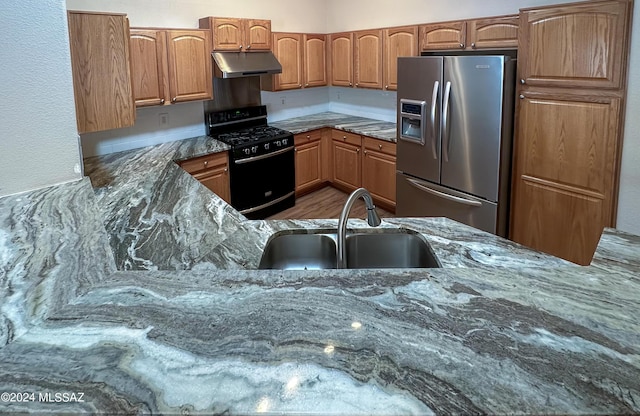 kitchen with stainless steel refrigerator with ice dispenser, black gas range oven, dark stone counters, and sink