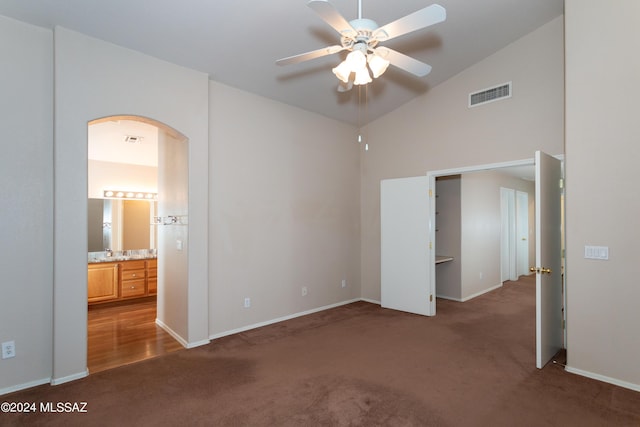 unfurnished bedroom with dark colored carpet, ensuite bathroom, vaulted ceiling, and ceiling fan