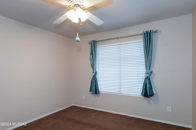 spare room with dark carpet and ceiling fan