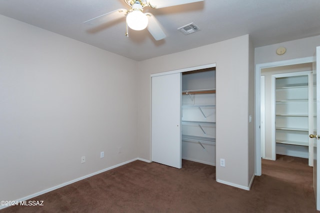 unfurnished bedroom featuring dark colored carpet, ceiling fan, and a closet