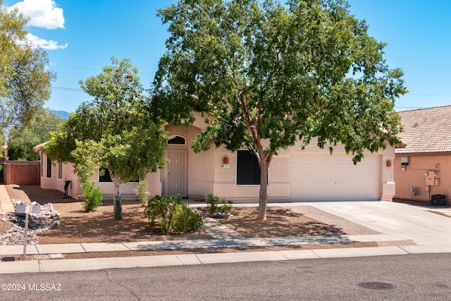 view of front of property with stucco siding, driveway, a tile roof, and a garage