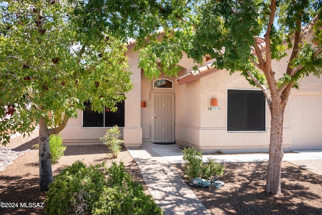 entrance to property with a garage, a tiled roof, and stucco siding