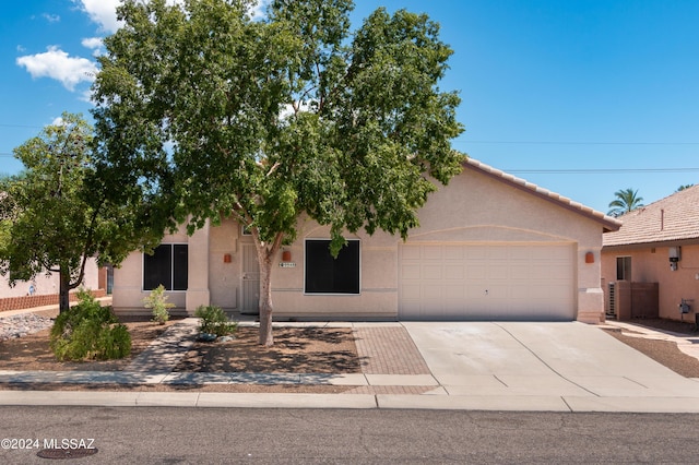 view of front of property featuring a tiled roof, stucco siding, an attached garage, and driveway