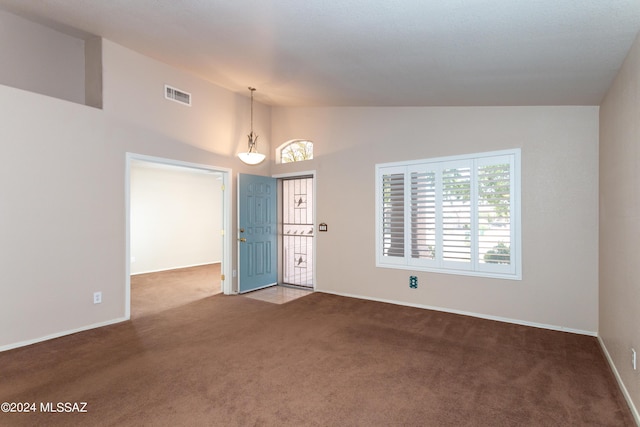 carpeted empty room featuring lofted ceiling, visible vents, and baseboards