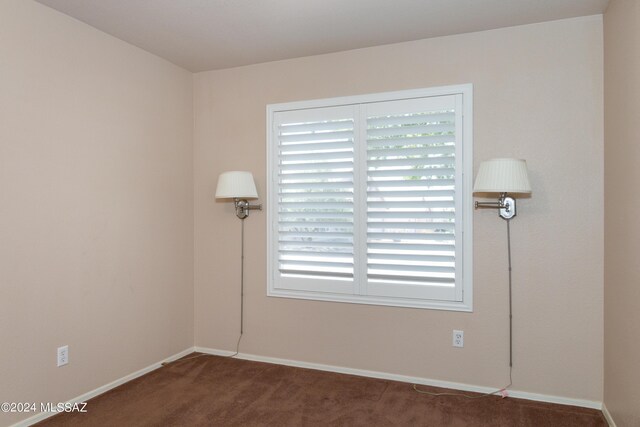 unfurnished room featuring dark colored carpet, lofted ceiling, and an inviting chandelier