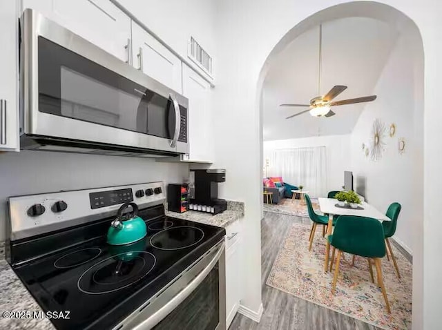 kitchen featuring white cabinets, light stone counters, hardwood / wood-style floors, ceiling fan, and appliances with stainless steel finishes