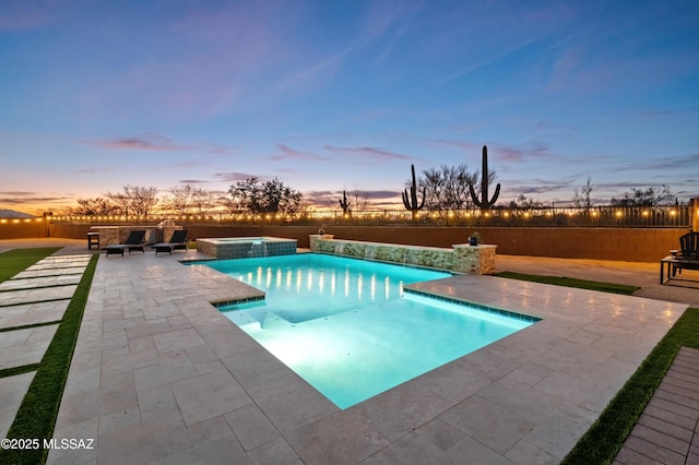 pool at dusk with an in ground hot tub and a patio