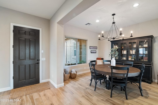 dining room with light hardwood / wood-style floors and a chandelier