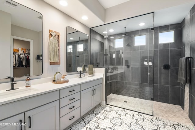 bathroom featuring tile patterned flooring, vanity, and tiled shower