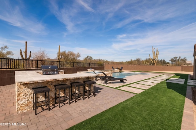 view of patio featuring exterior bar, an outdoor kitchen, area for grilling, and a fenced in pool