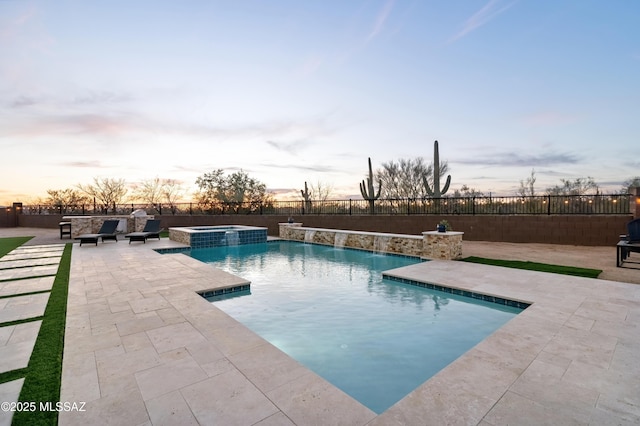 pool at dusk featuring a patio area, an in ground hot tub, and pool water feature