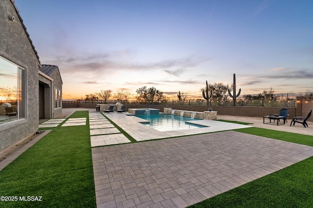 pool at dusk with a yard, pool water feature, and a patio area