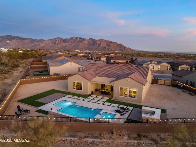 pool at dusk featuring a mountain view and a patio