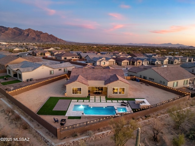 pool at dusk featuring a mountain view and a patio area