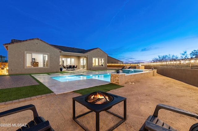 pool at dusk with a patio and an outdoor fire pit