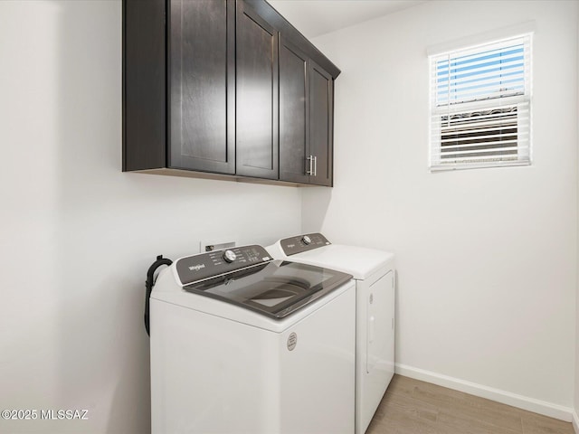 clothes washing area featuring light wood-type flooring, cabinet space, baseboards, and washing machine and clothes dryer