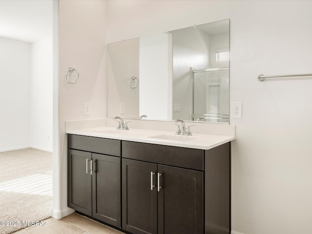 full bathroom featuring a sink, a shower stall, baseboards, and double vanity