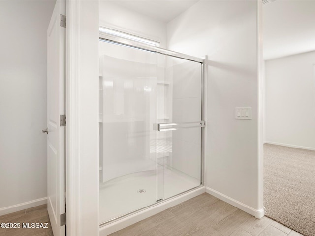 full bathroom with a shower stall, baseboards, and wood finished floors