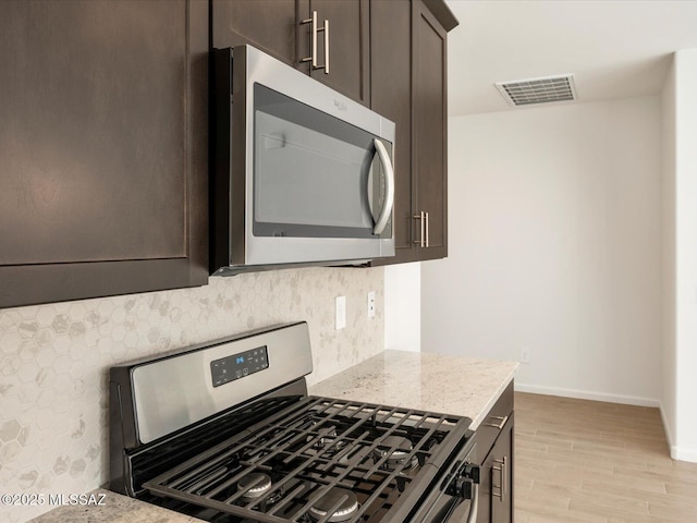 kitchen with visible vents, appliances with stainless steel finishes, tasteful backsplash, and dark brown cabinets