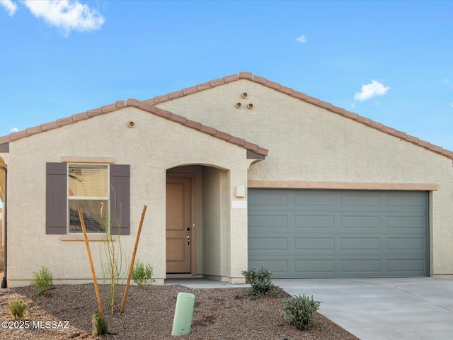 mediterranean / spanish home featuring a garage, concrete driveway, a tile roof, and stucco siding