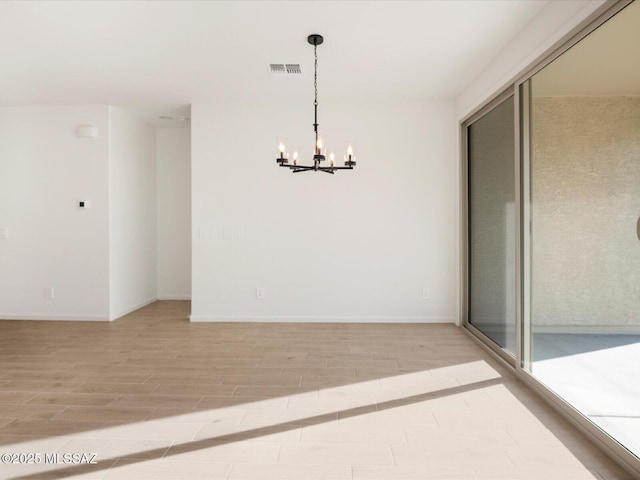 empty room with a chandelier, baseboards, visible vents, and light wood-style floors