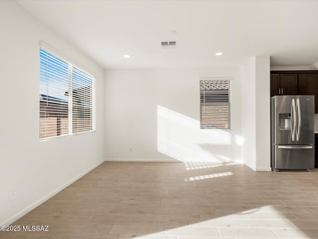 interior space featuring light wood finished floors, baseboards, stainless steel refrigerator with ice dispenser, and dark brown cabinets