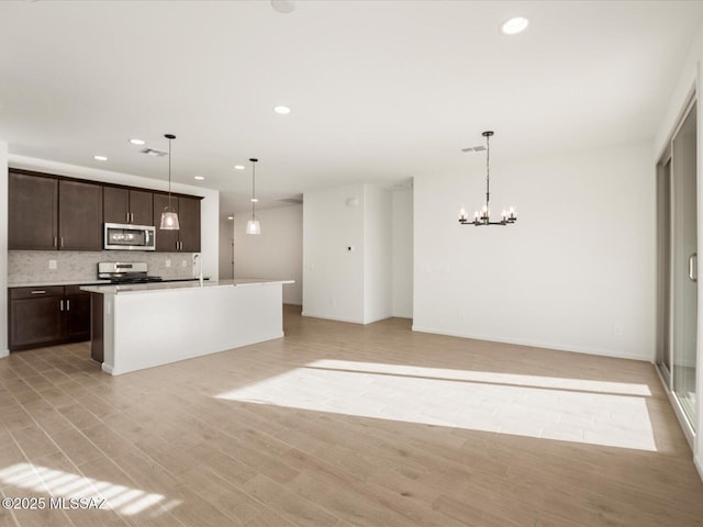 kitchen featuring light wood-style floors, stainless steel appliances, dark brown cabinets, and open floor plan