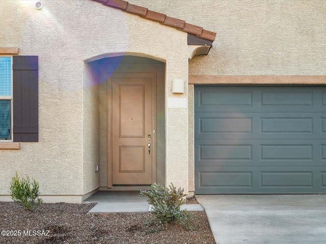 entrance to property with driveway and stucco siding