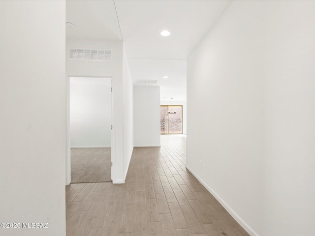 hall featuring light wood-style flooring, recessed lighting, visible vents, and baseboards