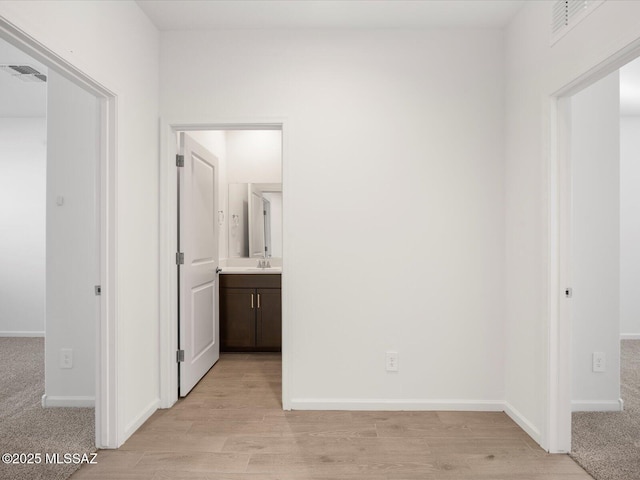 hallway featuring light wood-type flooring, visible vents, and baseboards