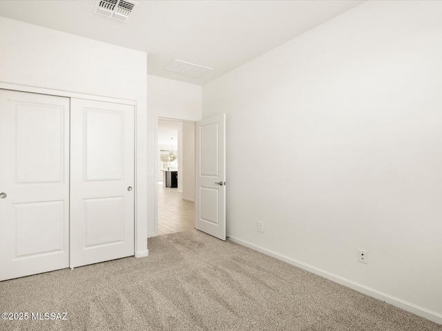 unfurnished bedroom with baseboards, carpet, visible vents, and a closet