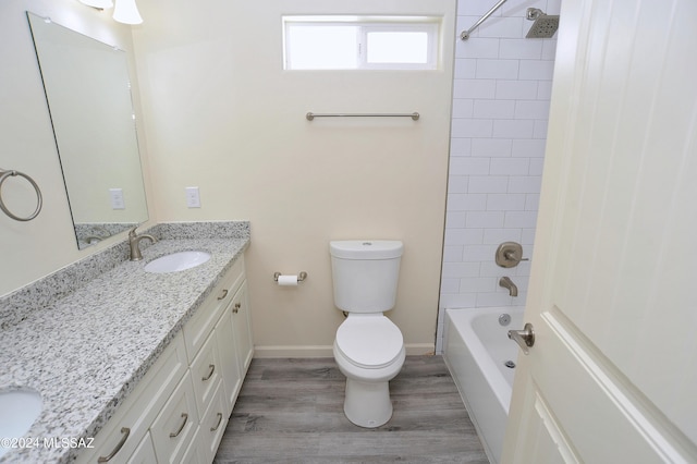 full bathroom featuring hardwood / wood-style floors, vanity, tiled shower / bath combo, and toilet