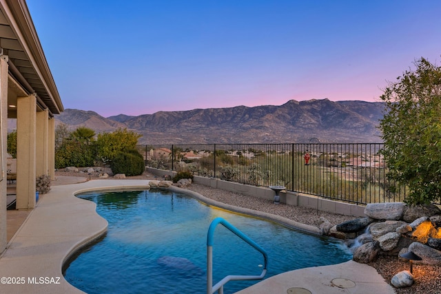 pool at dusk featuring a fenced backyard, a mountain view, and a fenced in pool