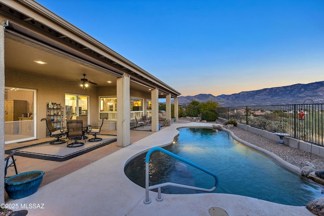 63111 E Mountain Crest Dr, Tucson, AZ 85739 - pool at dusk with a mountain view, a fenced backyard, a patio area, ceiling fan, and outdoor dining area