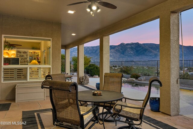 63111 E Mountain Crest Dr, Tucson, AZ 85739 - patio terrace at dusk featuring a patio area, a mountain view, ceiling fan, and outdoor dining space