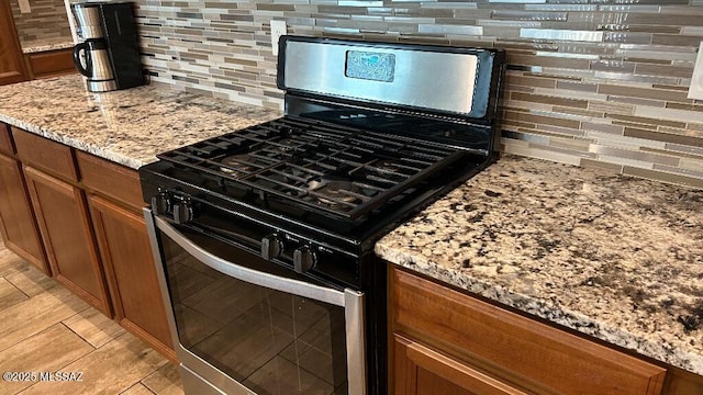 kitchen with gas stove, light stone counters, and backsplash