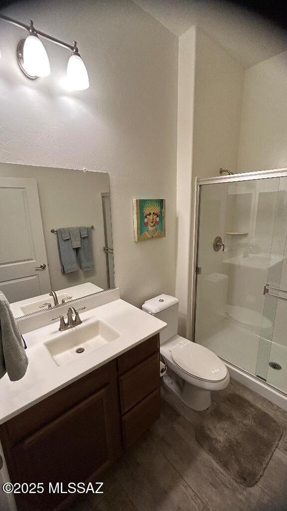 bathroom with vanity, toilet, a shower with door, and wood-type flooring