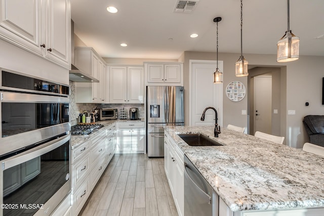 kitchen featuring sink, a center island with sink, white cabinetry, and stainless steel appliances