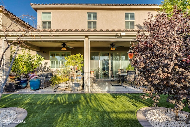 rear view of house featuring ceiling fan, a lawn, and a patio