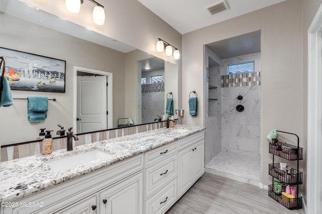 bathroom with tiled shower and vanity