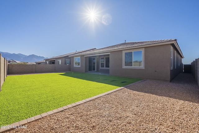 back of property featuring a yard, stucco siding, a patio area, a mountain view, and a fenced backyard