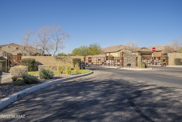 view of street featuring curbs, a gated entry, and traffic signs