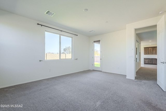 unfurnished room featuring baseboards, visible vents, and light colored carpet