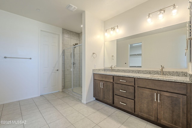 full bathroom with double vanity, visible vents, tile patterned floors, a shower stall, and a sink