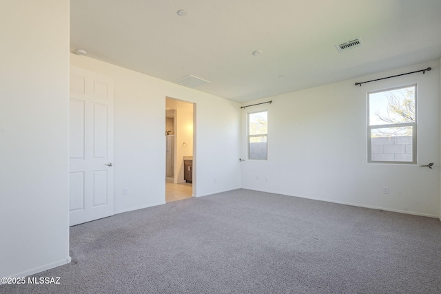 spare room with light colored carpet, visible vents, and baseboards