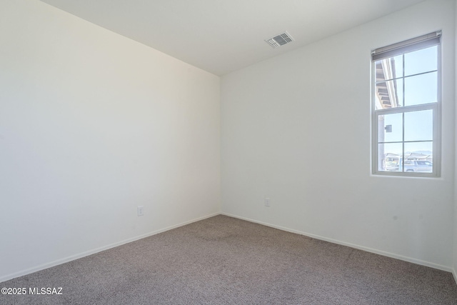 carpeted spare room featuring visible vents and baseboards